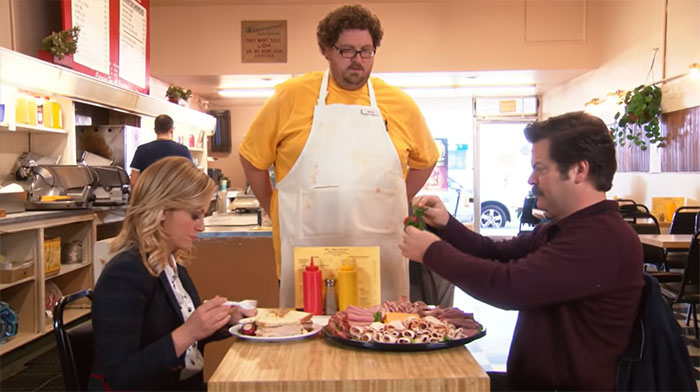 Ron Swanson removing salads from a large meat platter at a diner, highlighting his love for meat in life quotes.