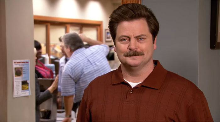 Ron Swanson smiling at the camera wearing a brown shirt, capturing a moment for Ron Swanson quotes on life.