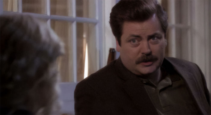 Ron Swanson with mustache talking indoors, embodying wisdom and humor related to Ron Swanson quotes on life.