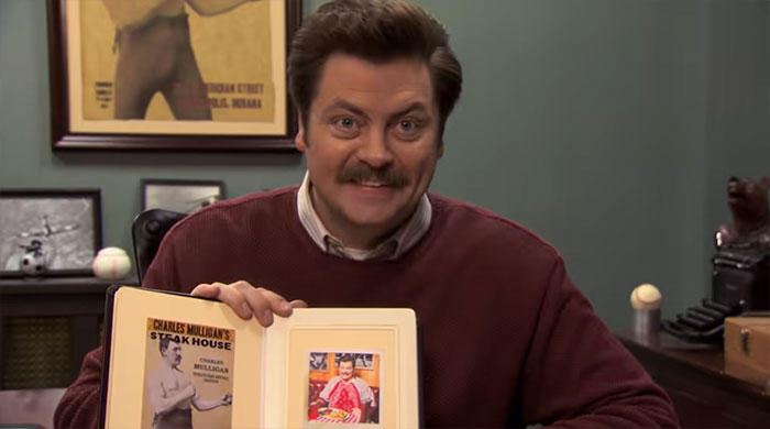 Ron Swanson smiling and showing a book, embodying personality from Ron Swanson quotes about life and wisdom.