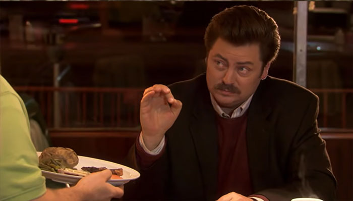 Ron Swanson talking with a waiter in a restaurant scene, illustrating iconic Ron Swanson quotes on life and wisdom.