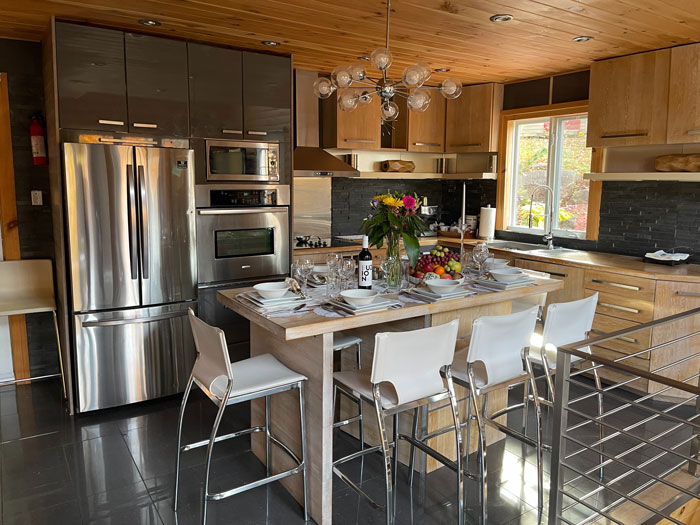 a kitchen with stainless steel appliances and a kitchen island with white bar chairs a kitchen with stainless steel appliances and a kitchen island with white bar chairs