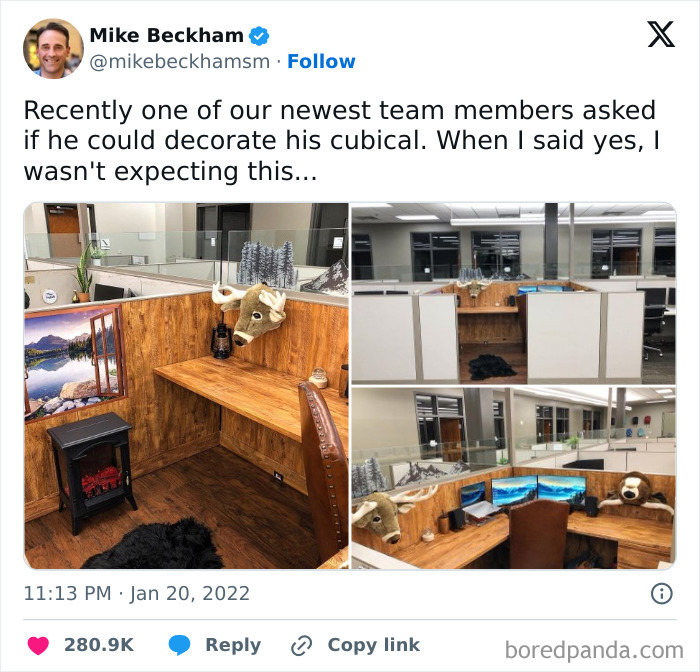 Office cubicle decorated with wood paneling, mounted deer head, cozy elements, and multiple monitors, showcasing relatable memes.