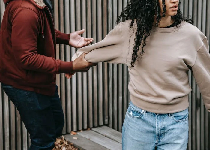 Maid of honor reacts emotionally as boyfriend holds her arm during a tense moment outside a wedding venue.