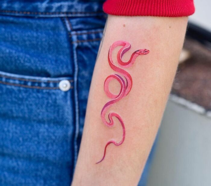 Red snake tattoo design on a forearm, showcasing intricate details and vibrant colors.