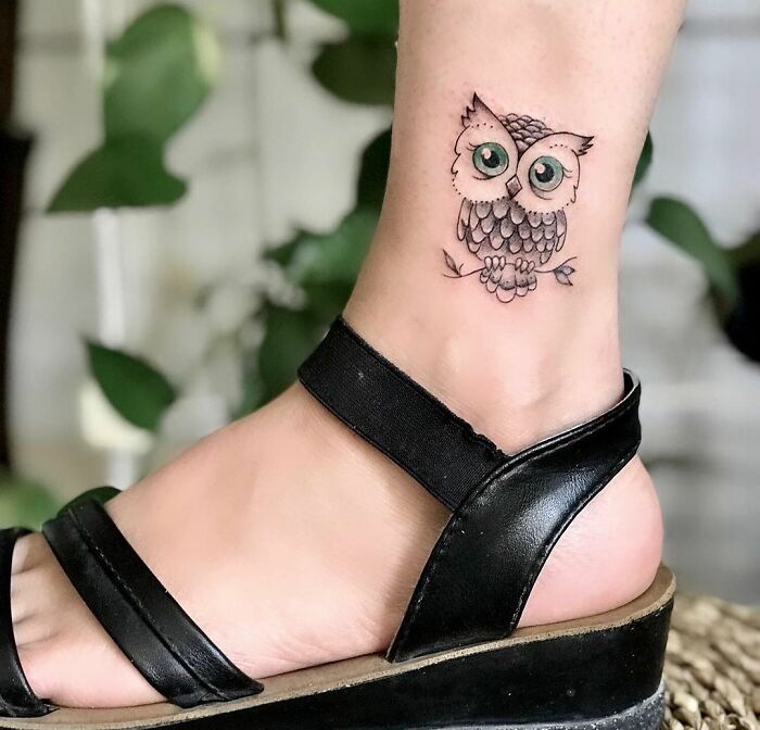 Owl design ankle tattoo with black sandals.