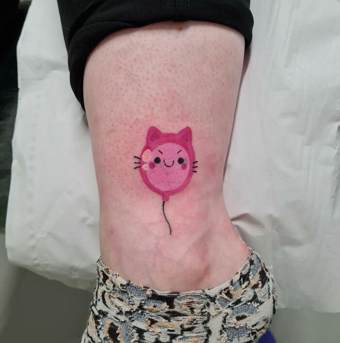 Cute ankle tattoo of a pink cat balloon design on a person's leg.