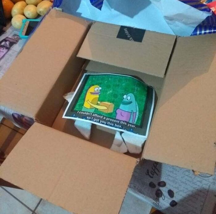 Open cardboard box with a funny birthday meme inside featuring cartoon characters and a humorous message.