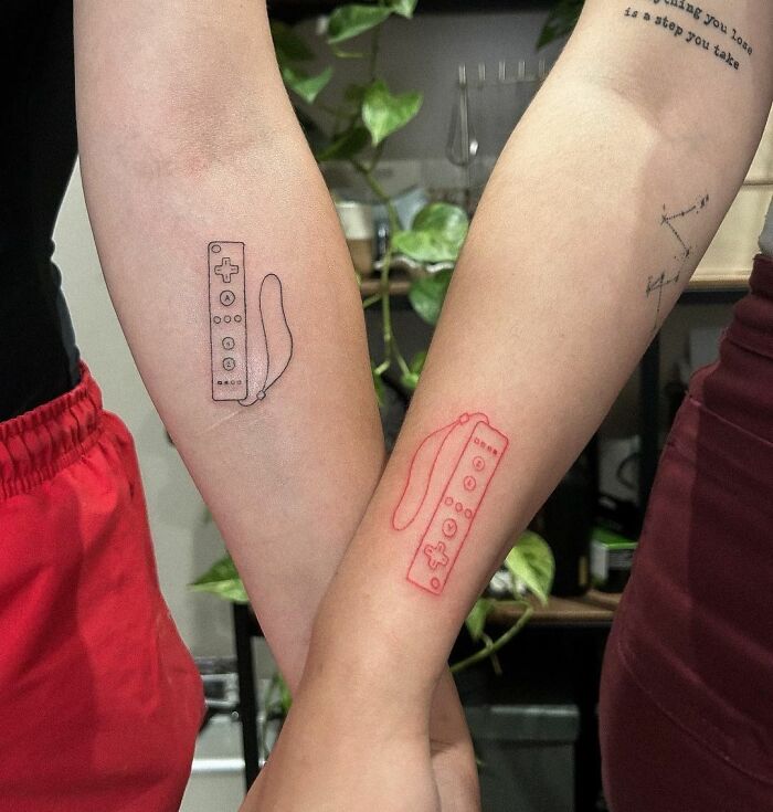 Two forearms with video game controller tattoos, perfect for hardcore gamers.