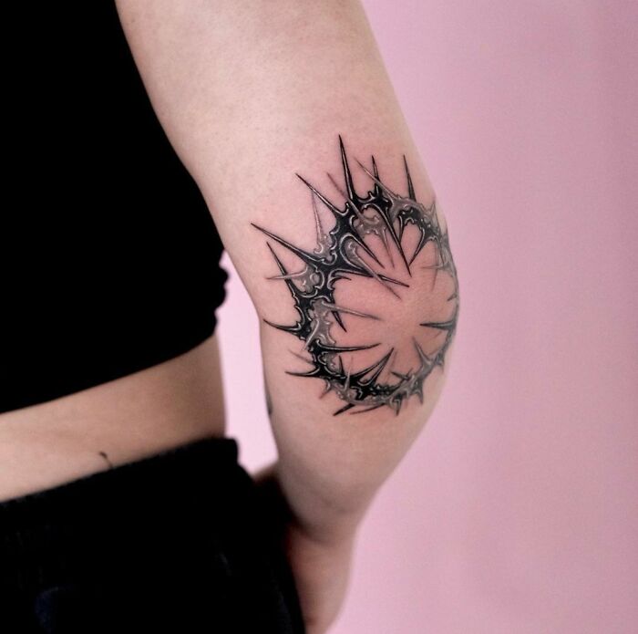 Stylish elbow tattoo in black ink with intricate sharp patterns, perfect for unique body art inspiration.