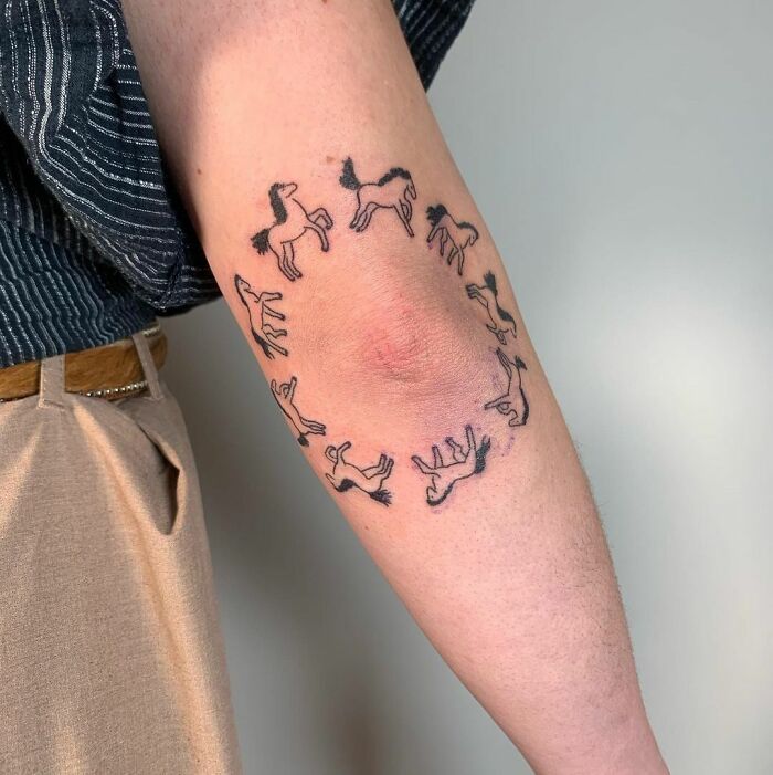 Circular horse design on elbow tattoo.