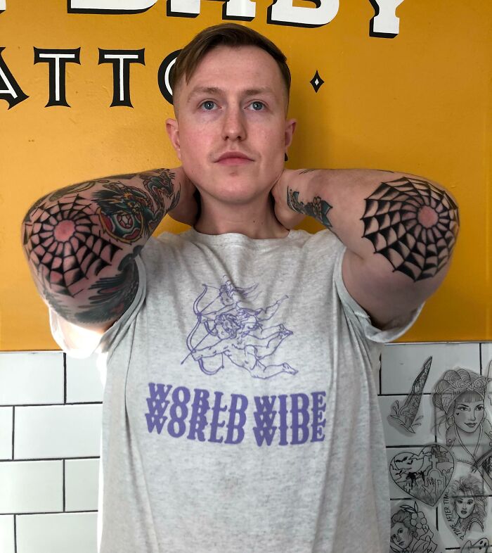 Person showcasing dazzling elbow tattoos with geometric patterns on both arms against a vibrant background.