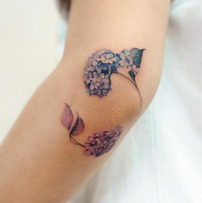 Floral elbow tattoo featuring purple hydrangeas on skin, showcasing a creative and dazzling design choice.