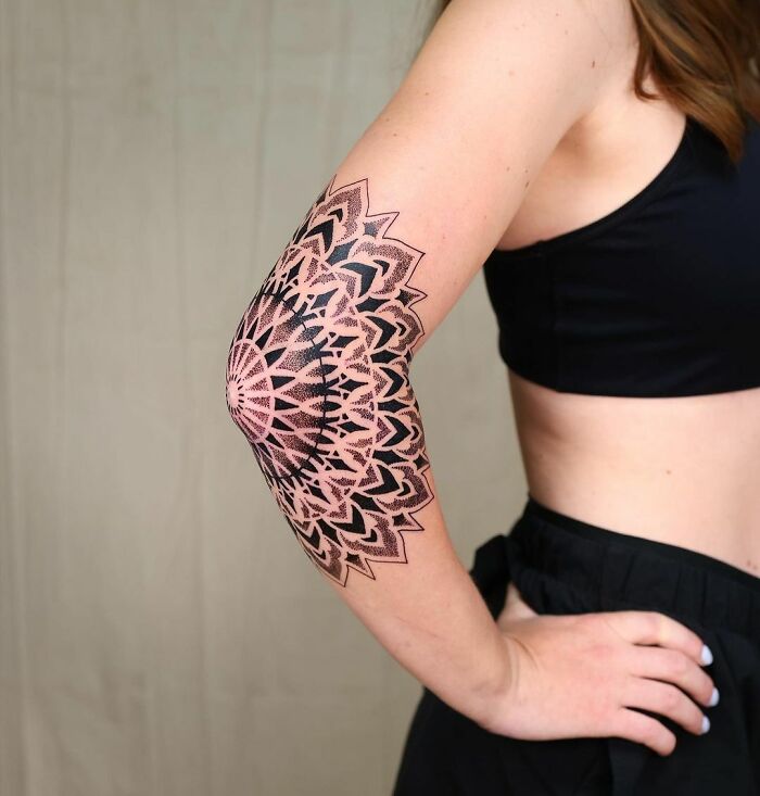 Mandala design elbow tattoo on a person's arm, showcasing intricate patterns.