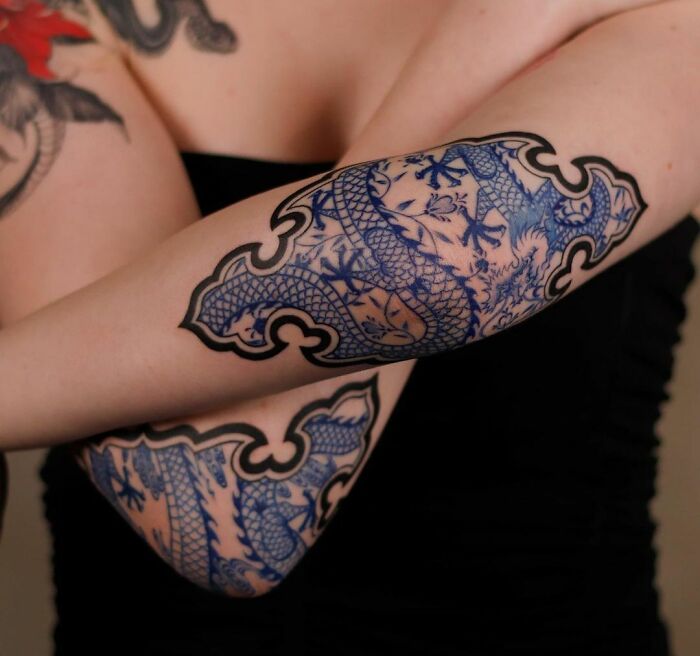 Blue and black ornamental design on an elbow tattoo, featuring intricate patterns.