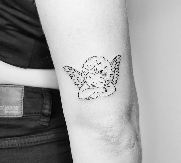 Angel design elbow tattoo on a person's arm, showcasing a serene expression with wings.