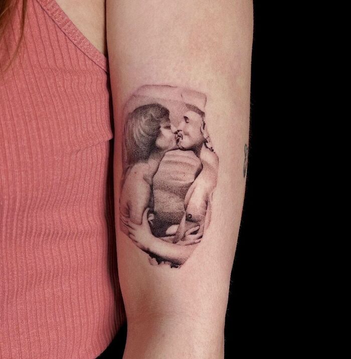 Tattoo of a couple kissing, symbolizing family honor and remembrance, on an arm wearing a pink shirt.