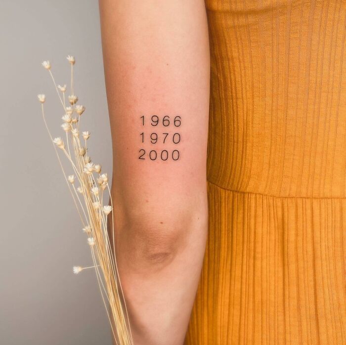 Arm tattoo with significant dates, symbolizing family bonds.