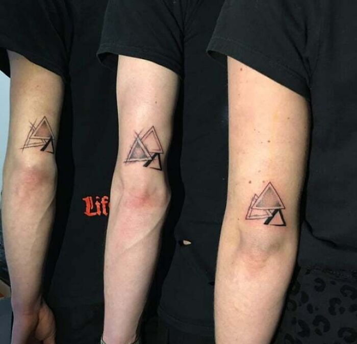 Three arms with geometric family tattoos, symbolizing unbreakable bonds, in black ink on inner arms.