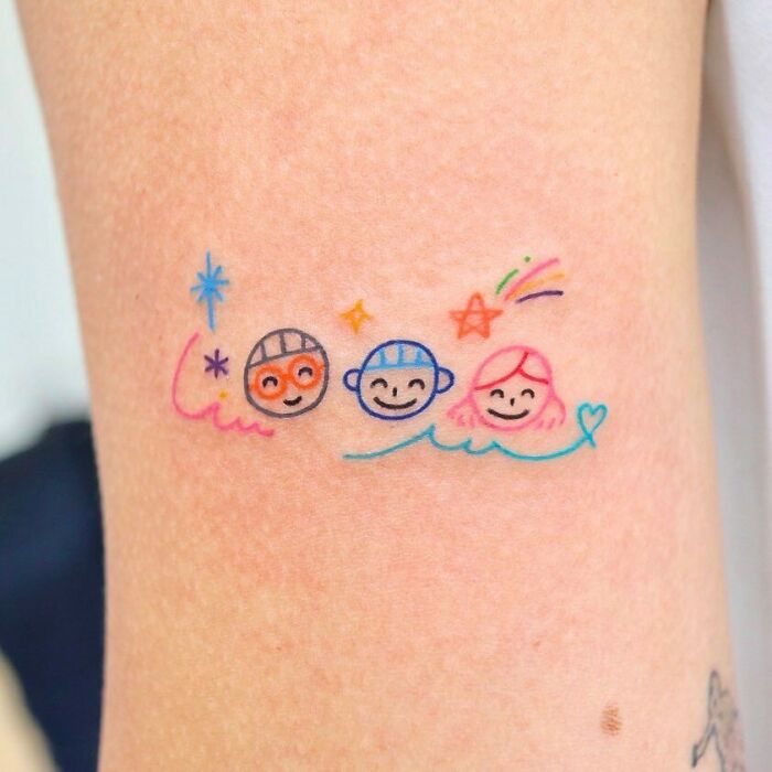 Colorful family tattoo symbolizing bonds, featuring three smiling faces with stars and heart accents.