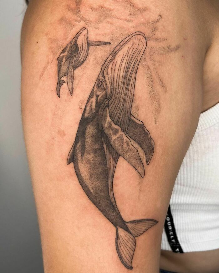 Family tattoo featuring a parent and baby whale, symbolizing unbreakable bonds and unity.