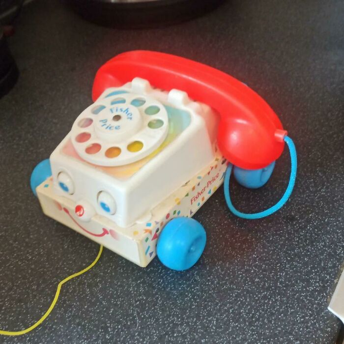 Vintage Fisher Price toy phone with red handset and blue wheels, a funny reminder of people getting old faster than expected.