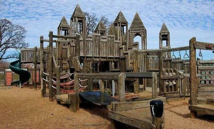 Large wooden playground structure resembling a castle, showcasing a painfully funny example of people getting old faster.