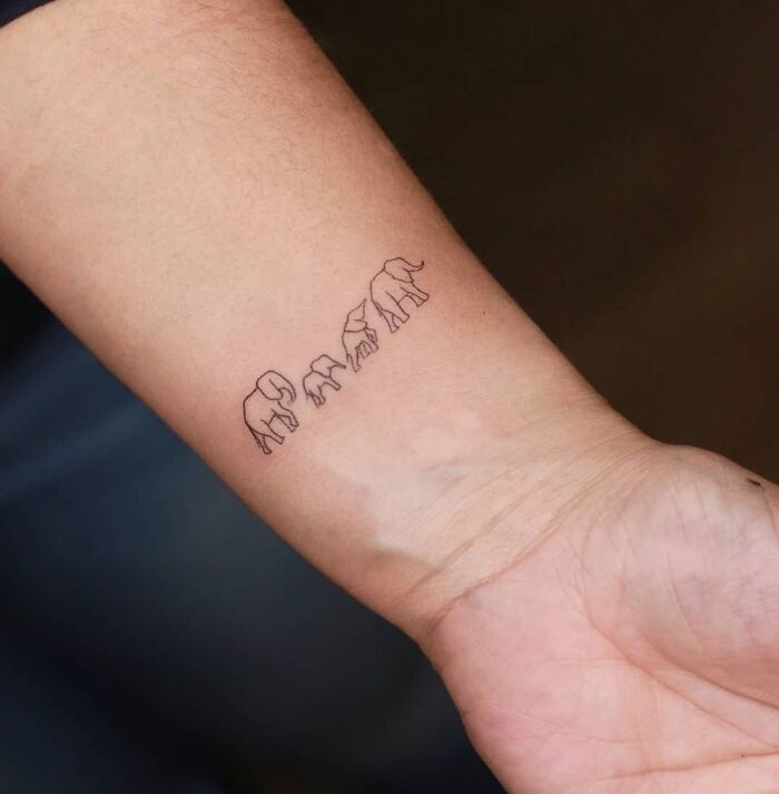 Elephant family tattoo on forearm symbolizing unbreakable bonds and unity, showcasing family tattoo ideas.