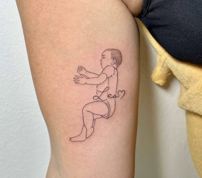 Tattoo of a baby with the name "Leo" symbolizing family bonds, inked on an arm.