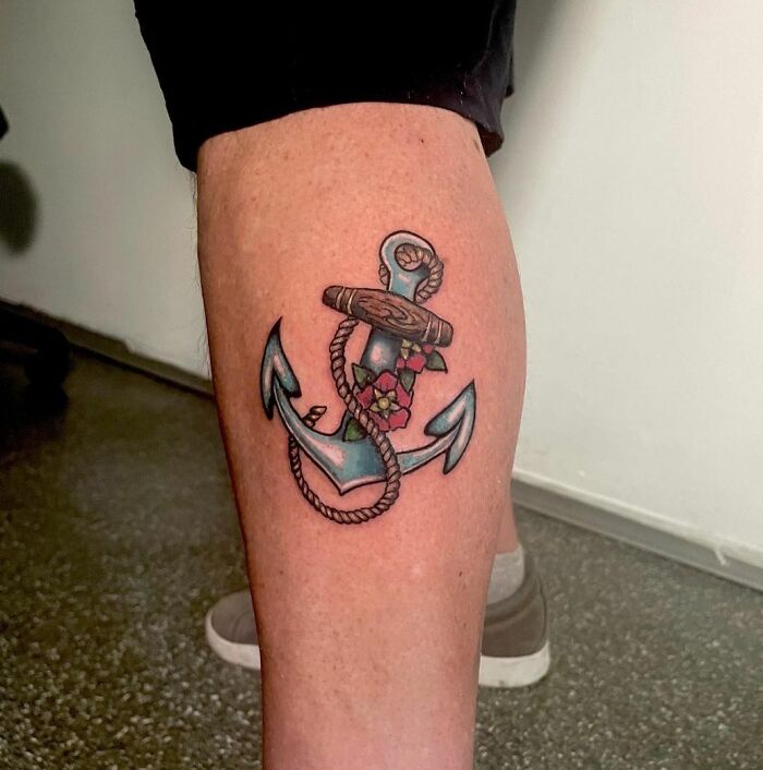 Anchor tattoo with floral design on a person's calf, symbolizing family honor.