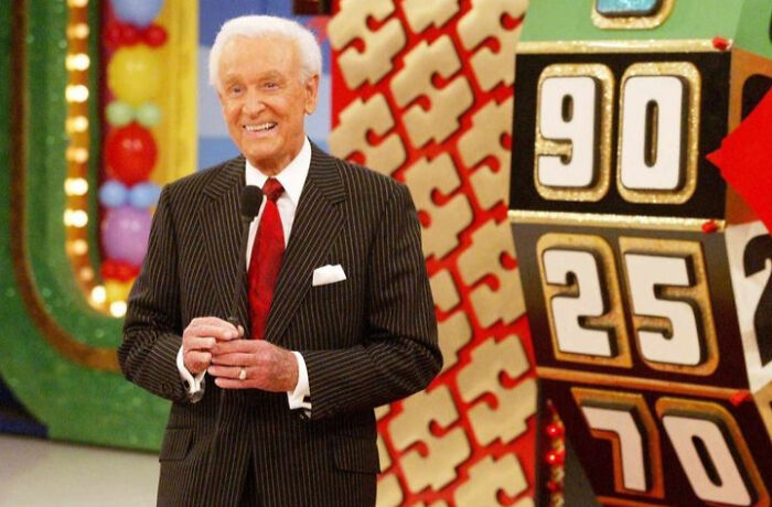 Man in a striped suit on a game show set, humorously illustrating aging faster than expected.