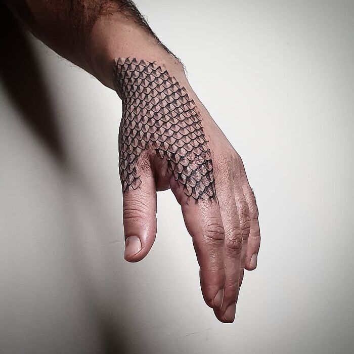 Hand with a snake scale tattoo design covering the back, showcasing intricate pattern details.