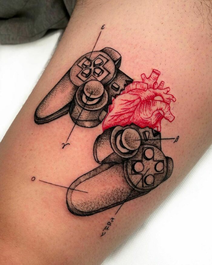 Video game tattoo featuring a game controller and realistic anatomical heart design on skin.