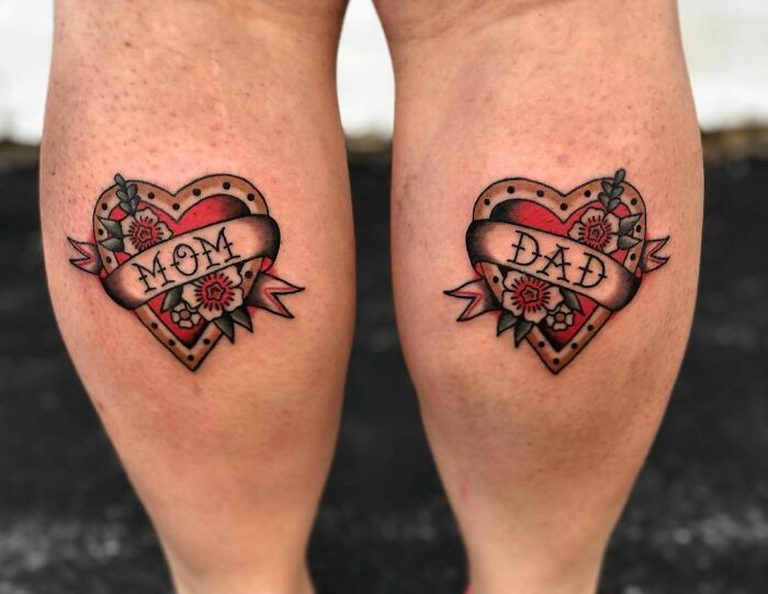Heart tattoos on calves with "Mom" and "Dad" banner, floral design, memorial tattoo idea.