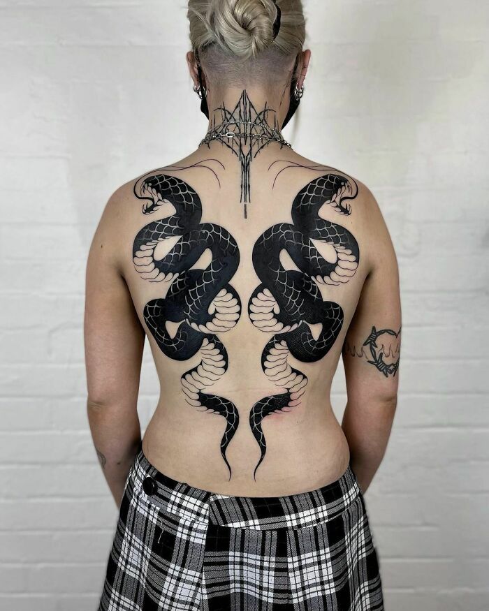Back with intricate snake tattoos featuring two symmetrical black serpents wrapping across the skin.