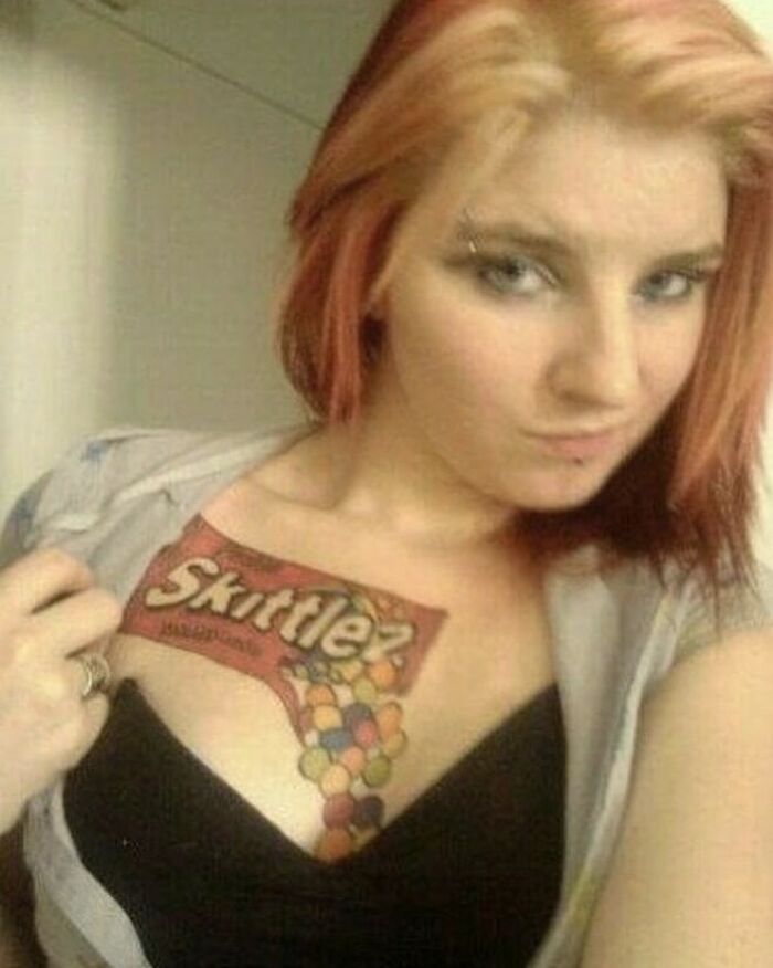 Close-up of a woman showing a colorful Skittles tattoo on her chest, representing a lesson in tattoo failures.
