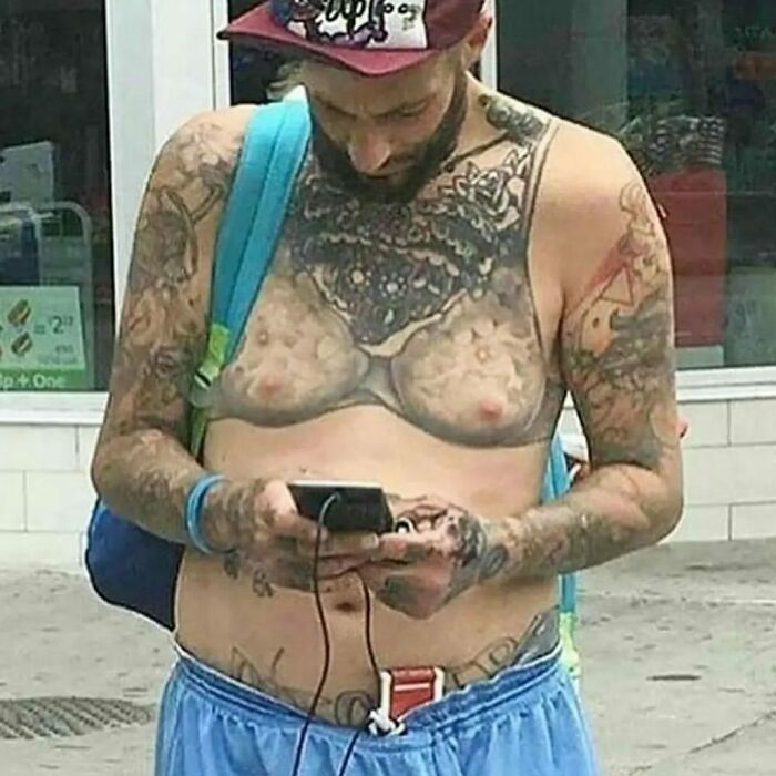 Man with unique tattoos using a smartphone on the street, illustrating epic failures turned lessons in ink.