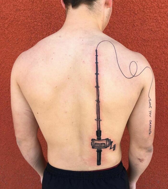 Back tattoo of a fishing rod with "Love You Grandma" text, symbolizing family memorial.