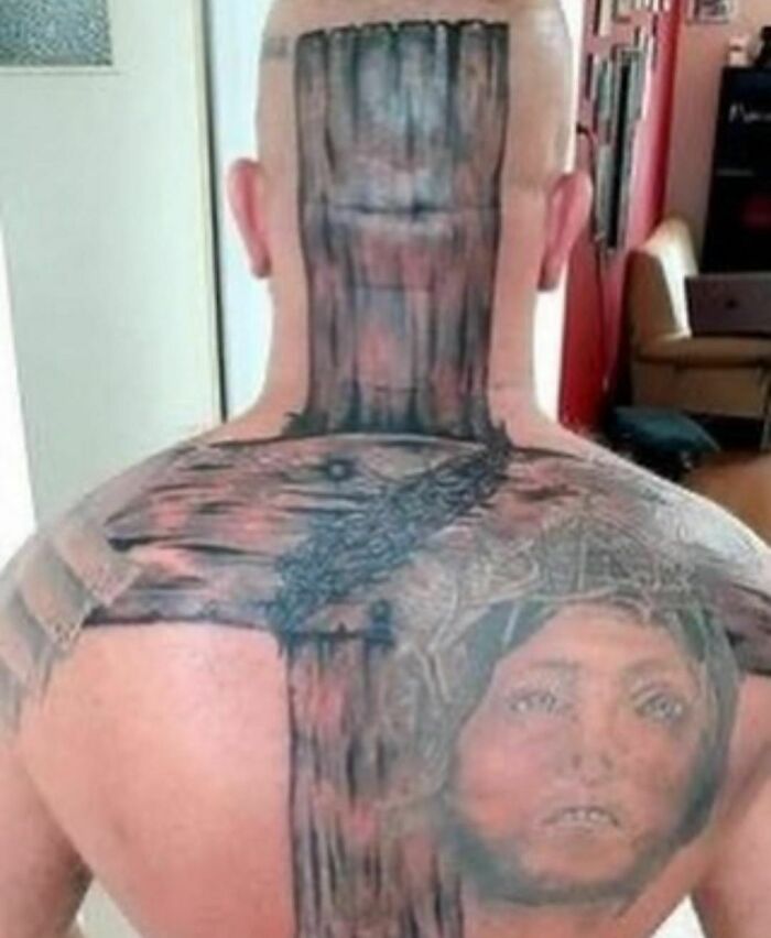 Tattoo fail showcasing a wooden cross extending from neck to back with a face, illustrating a lesson in ink.