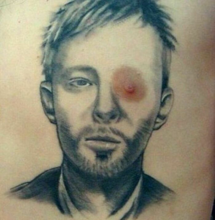 Tattoo fail showcasing a portrait with a n****e positioned as an eye.