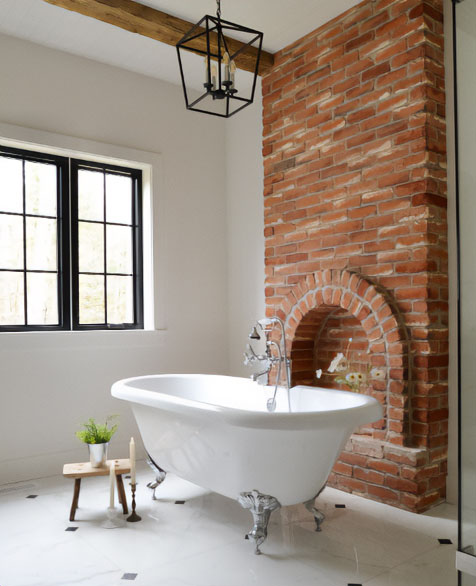 White clawfoot tub near the brick wall.