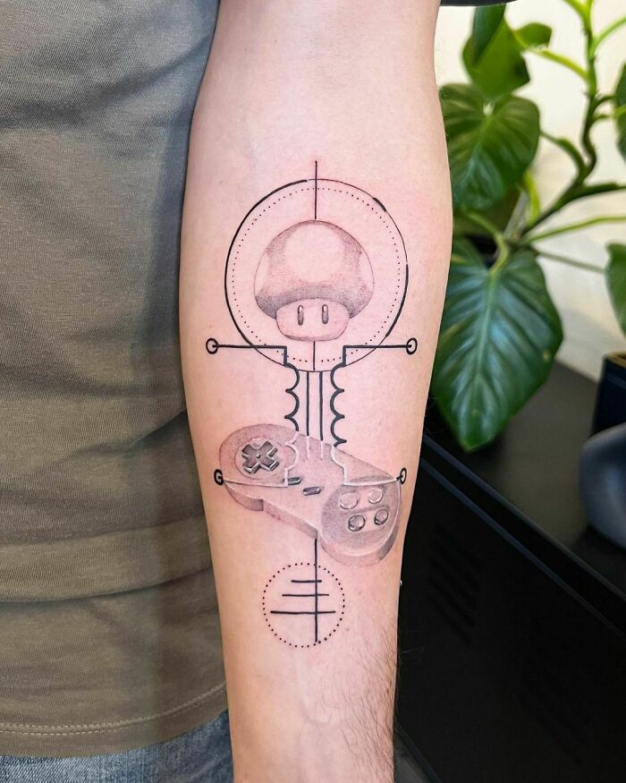 Super Mario video game tattoo featuring a controller and mushroom design on a forearm, ideal for hardcore gamers.
