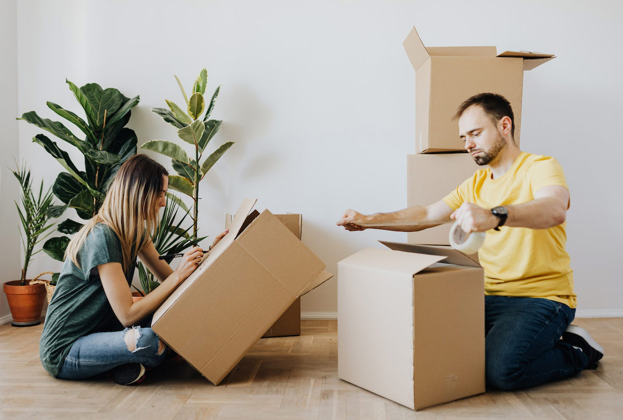 A couple is sealing carton boxes