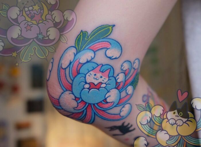 Colorful cat design elbow tattoo featuring flowers and swirling patterns.