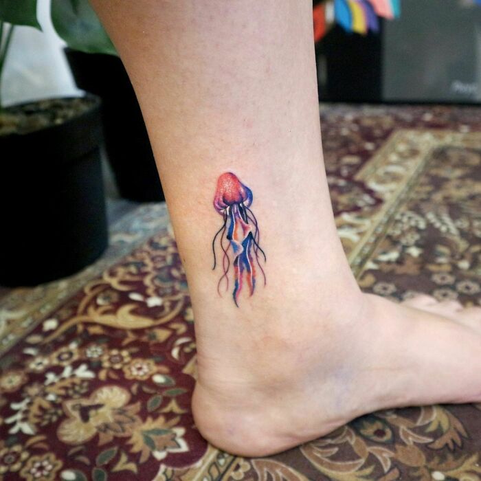 Jellyfish ankle tattoo on leg, showcasing intricate design and vibrant colors, exemplifying ankle tattoo care ideas.