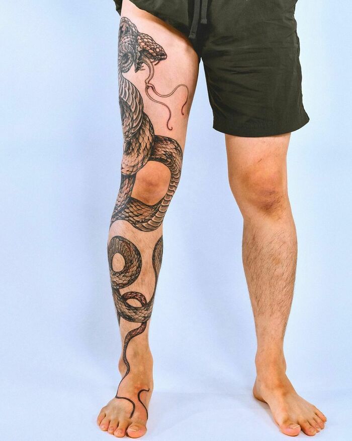 Leg with intricate snake tattoo wrapping around from thigh to ankle.