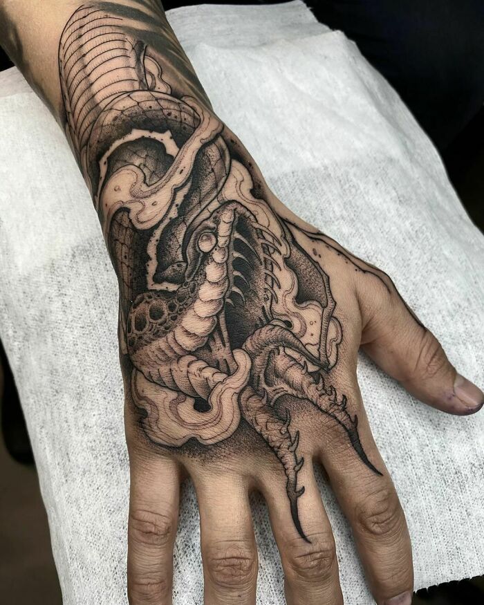 Detailed snake tattoo design inked on a person's hand.
