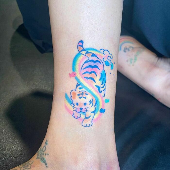 Colorful tiger ankle tattoo with rainbow accents, showcasing creative tattoo inspiration.