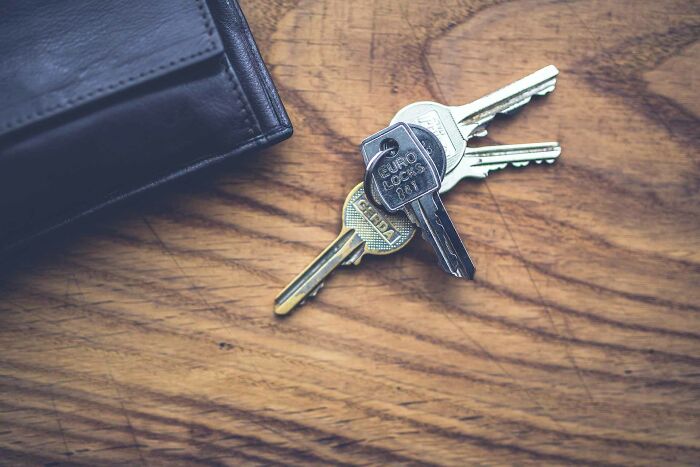 Keys and wallet placed on a wooden desk, symbolizing everyday items for sharing useless facts to impress friends.