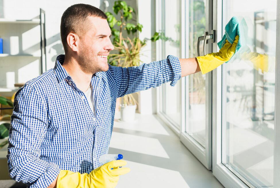 A man cleaning a window in sunlight